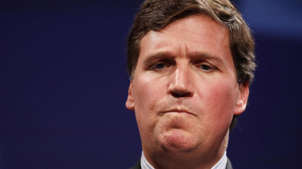 Tucker Carlson looks thoughtful and annoyed with his mouth pinched