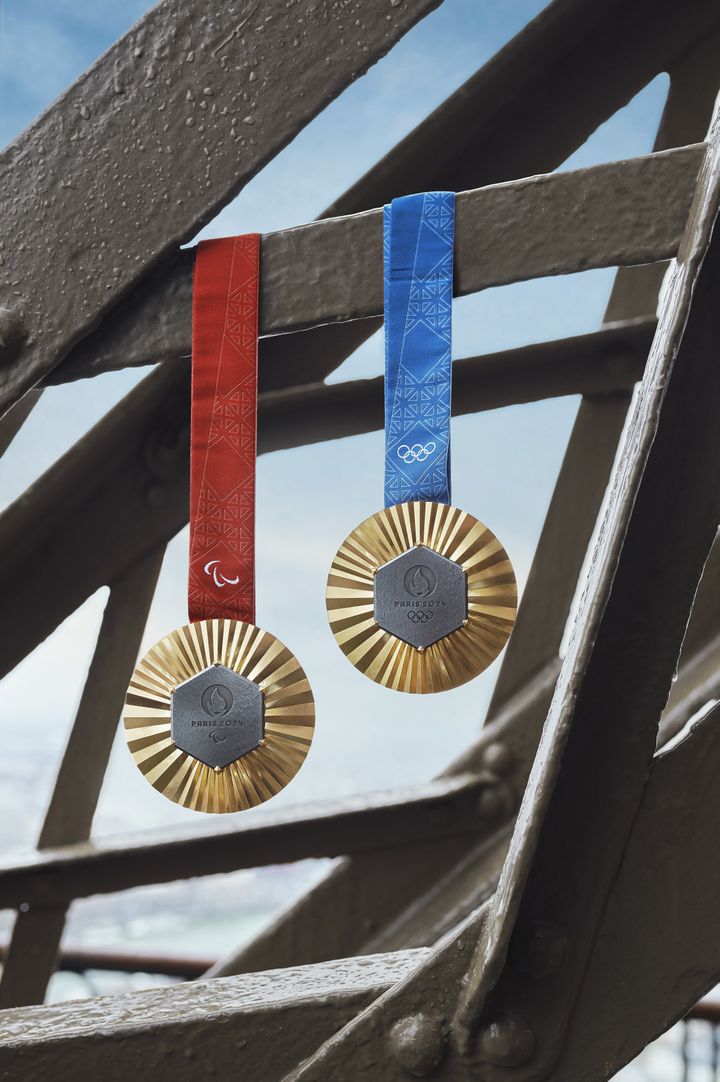 The Paralympic (red ribbon) and Olympic (blue ribbon) gold medals hang from the Eiffel Tower.  (© Paris 2024)