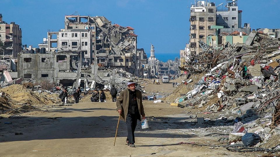 A resident of Gaza City walks through a completely destroyed neighborhood