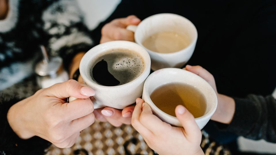 Hands hold cups with coffee and tea
