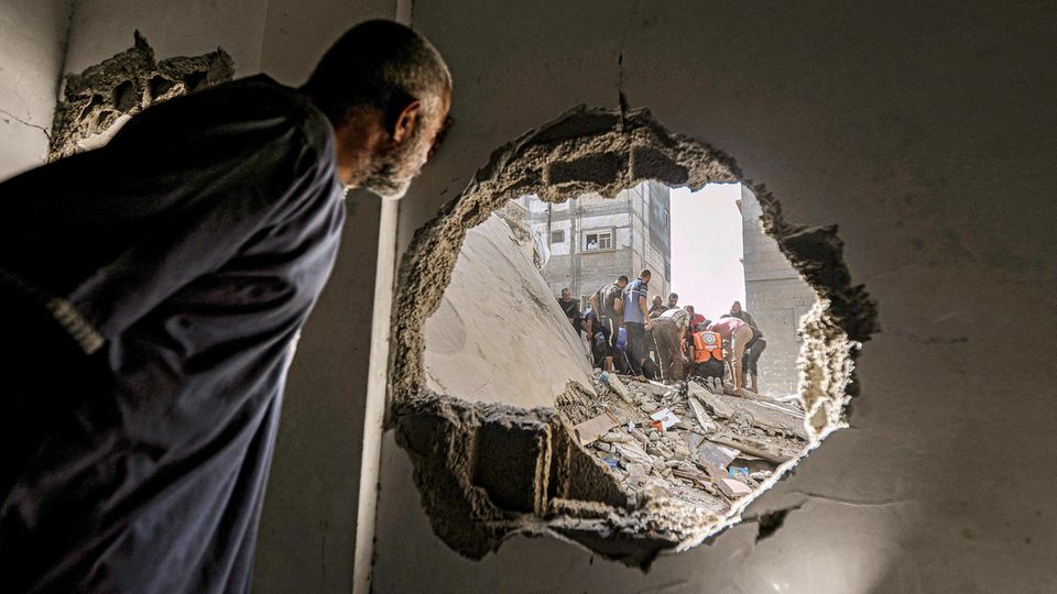 A man looks through a hole in the house wall