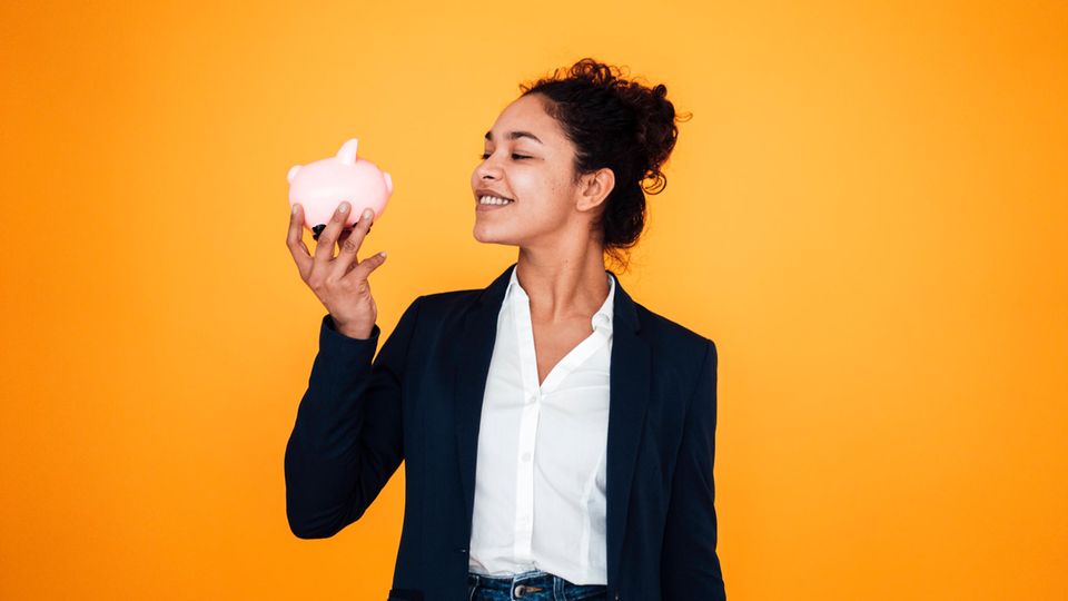 Young woman looks at a piggy bank