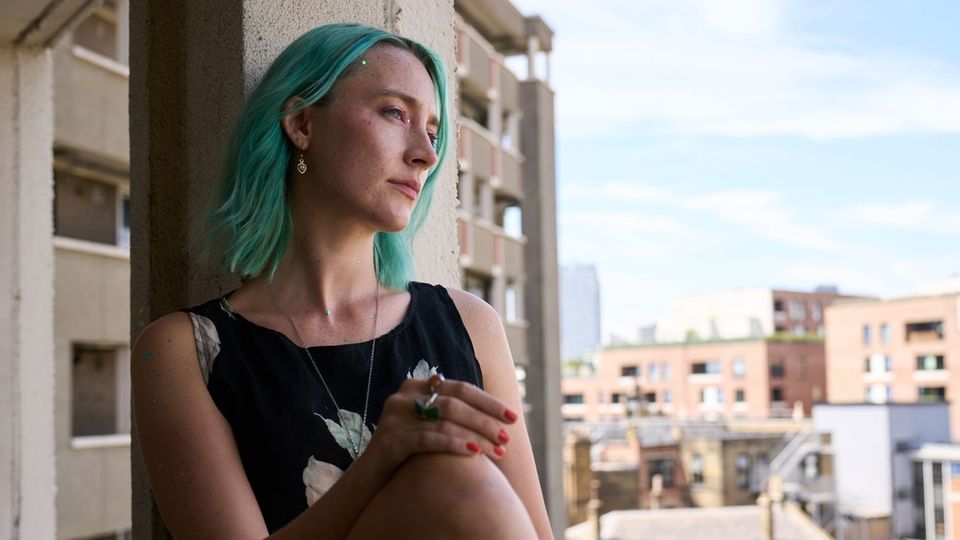 Actress Saoirse Ronan in "The Outrun" with green hair sitting at the window