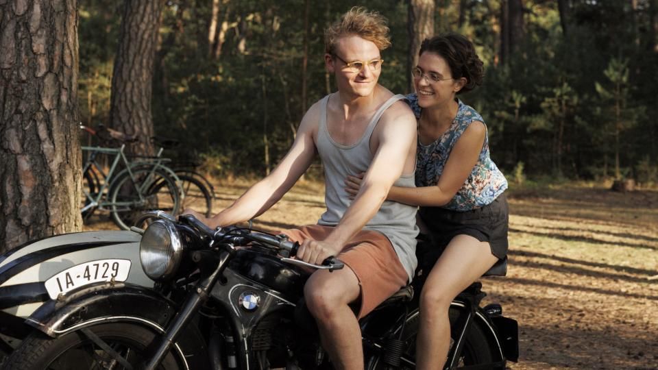 Hans (Johannes Hegemann) and Hilde (Liv Lisa Fries) in summer clothes on an old motorcycle