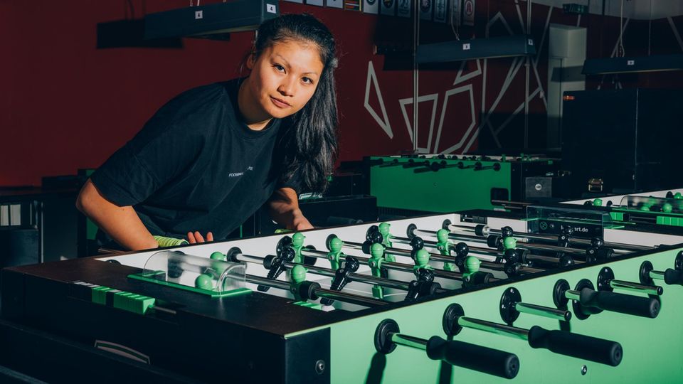 Linh Tran leans slightly forward on a table football and looks into the camera
