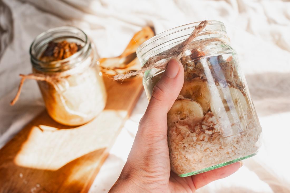 Woman holding a jar of overnight oats with bananas and walnuts