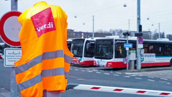 Standing Hamburger Hochbahn buses can be seen in the background.  In the foreground there is a vest with the logo of the ver.di union.  © picture alliance 