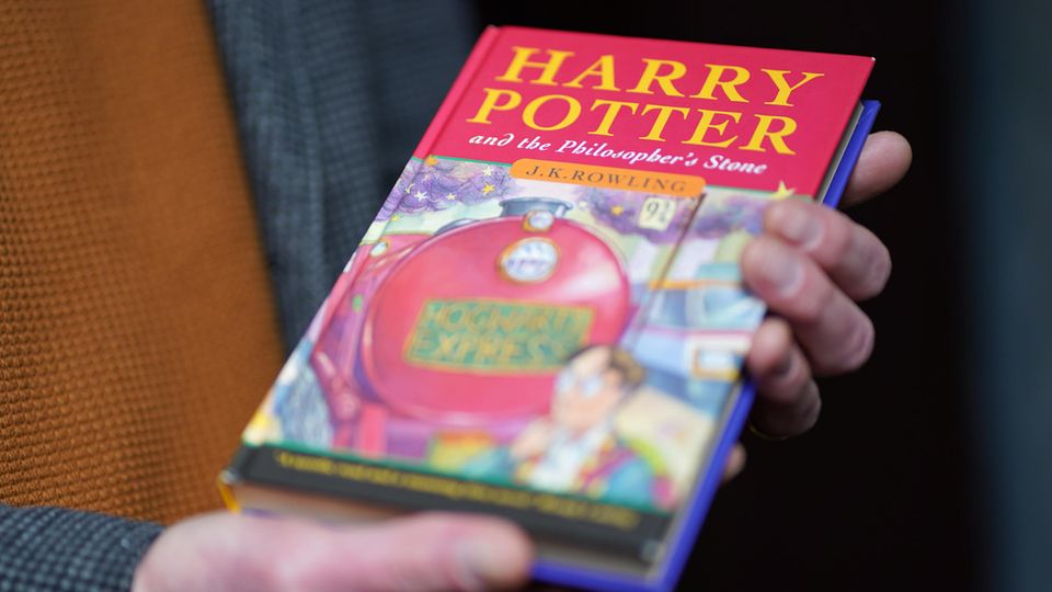 An auctioneer holds a first edition of the first Harry Potter volume
