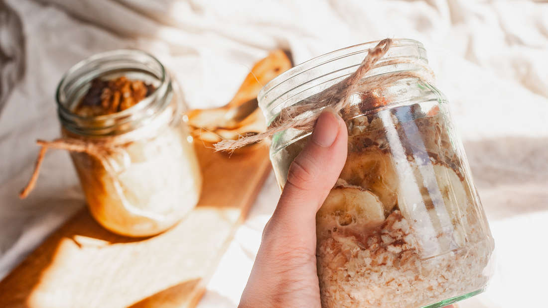 Woman holding a jar of overnight oats with bananas and walnuts