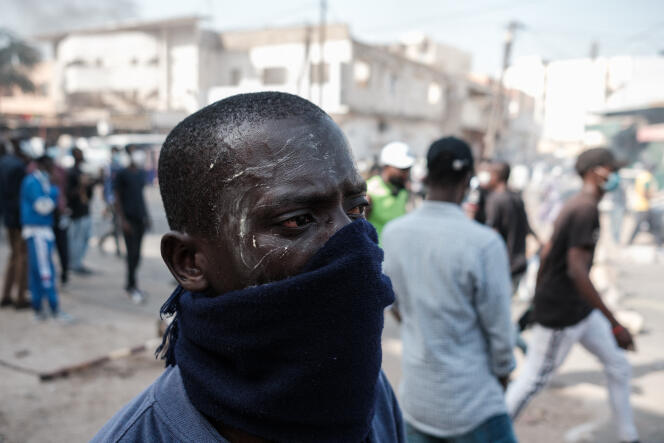 A protester protects himself from tear gas during clashes with the police, in Dakar, February 9, 2024.