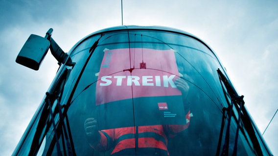 An employee sticks a strike poster on a tram.  © picture alliance/dpa Photo: Julian Stratenschulte