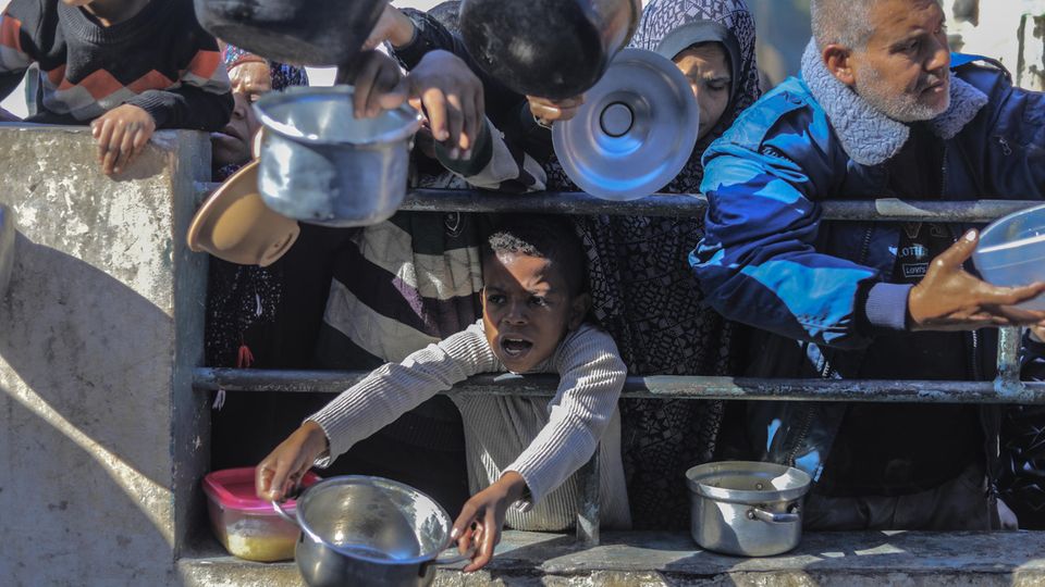 In Gaza, people with empty pots in their hands wait for an aid shipment to be distributed
