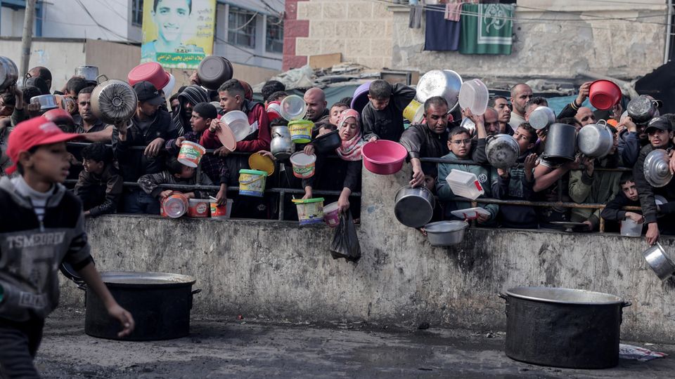 Their faces are drawn and tired: Palestinians wait for food at a food bank in a refugee camp in the southern Gaza Strip. 