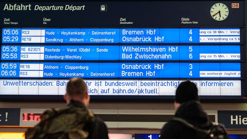 Delays: Travelers stand at the train station in the morning and look at the Deutsche Bahn display board:
