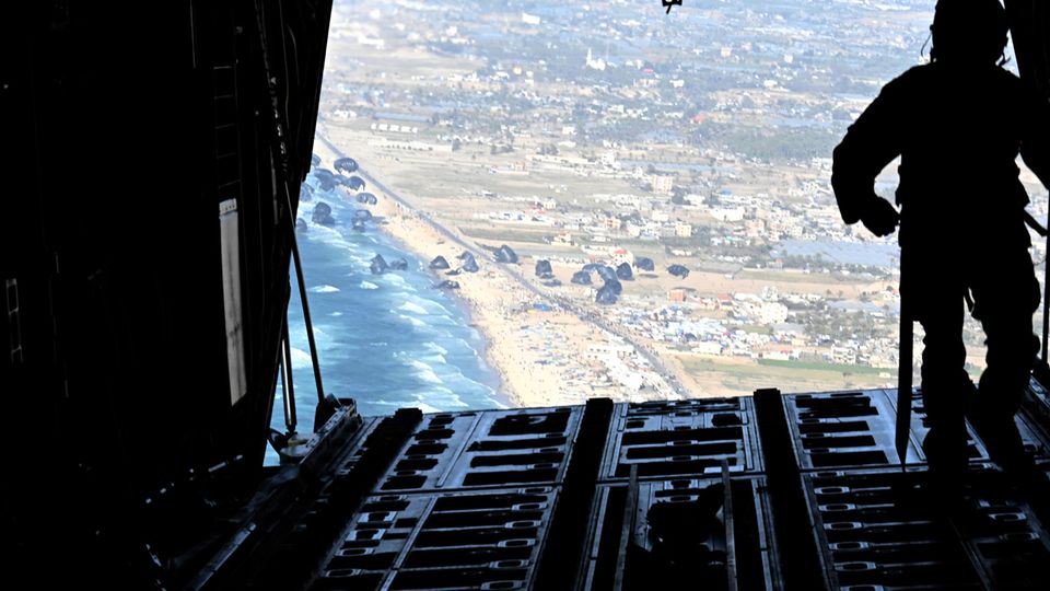 US Air Force planes parachute to drop pallets of supplies onto the beach in Gaza