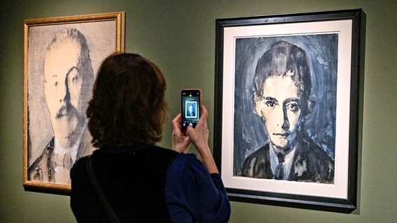 A woman uses her smartphone to photograph a painting by Franz Kafka - painted by Siegfried Herz - in an exhibition in Prague © picture alliance / CTK Photo: CTK Photo/Vit Simanek, paintings by Siegfried Herz