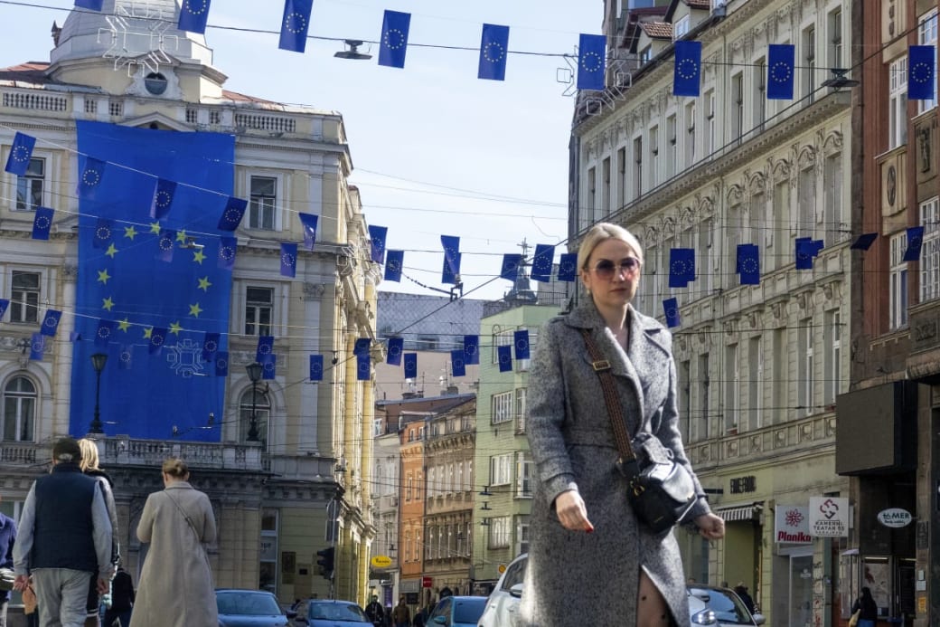 A woman walks under the European Union flags in one of the main streets of Sarajevo.  Photo: Eldar Emric/AP/dpa