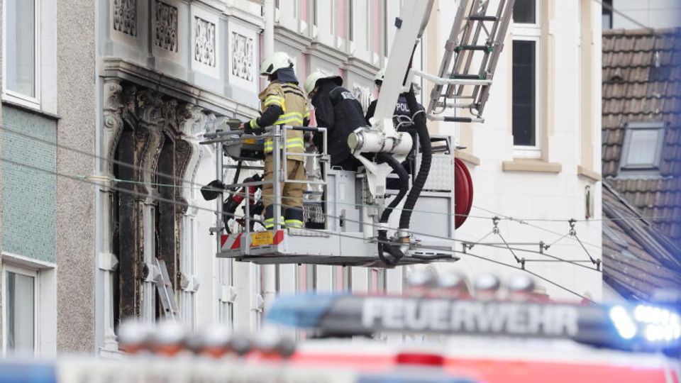 Solingen: Firefighters stand in the basket of a turntable ladder in front of an apartment building where there was a fire