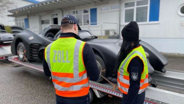 Superhero car: Two customs clearance officers stand in front of the car during a customs import inspection "Batmobile"which is on a trailer.