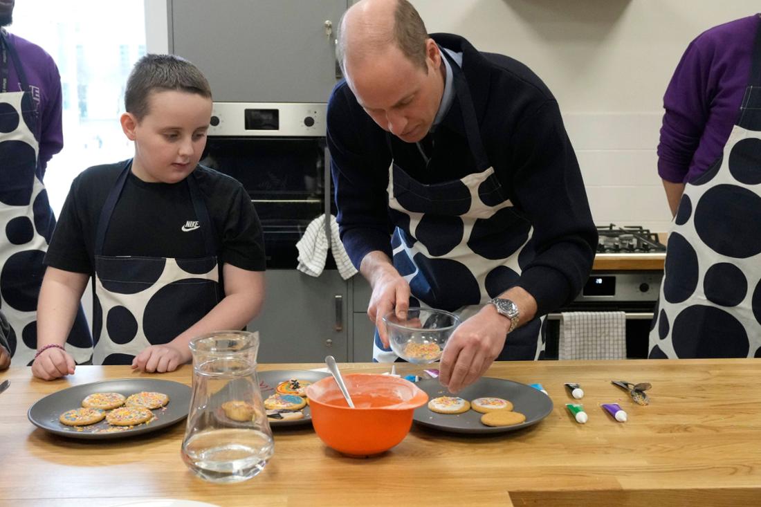 Prince William decorates cookies with a boy.