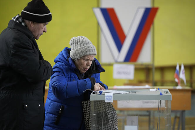 An elderly couple prepares to vote at a polling station in a school gymnasium during the presidential election, in St. Petersburg, Russia, Friday, March 15, 2024.