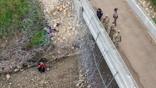 U.S. soldiers and law enforcement officers on a bridge above a group of immigrants who crossed the Rio Grande to enter the United States, in Eagle Pass, Texas, March 18, 2024 .